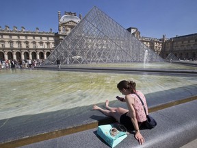 FILE - In this Aug.17, 2016 file photo, a woman cools off her legs in the Louvre fountain next to the Pyramid in Paris. Paris' Louvre Museum welcomed 8.1 million visitors in 2017, up 10 percent on the year before, a sign of tourism revival in the French capital. Tourism in the country took a hit in 2016 after a series of attacks by Islamic extremists.