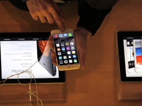 FILE - In this Sept.19, 2014 file photo, a customer checks the iPhone 6, in Paris. A French prosecutor office said Tuesday Jan.9, 2018 an investigation into Apple over alleged planned obsolescence of some of its smartphones has been opened. It follows a legal complaint filed in December by pro-consumer group Halte a l'obsolescence programmee (Stop Planned Obsolescence). Under a 2015 law, it is banned to intentionally shorten lifespan of a product in order to incite customers replace it.