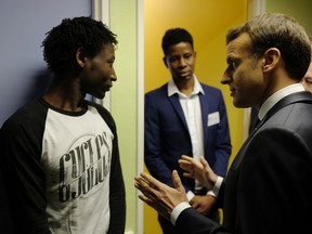 French President Emmanuel Macron talks to Ahmed Adam, left, from Sudan during his visit to a migrant center in Croisilles, northern France, Tuesday, Jan.16, 2018. Macron is making a foray into the symbolic heart of France's migrant problem with a visit to the port city of Calais, where hundreds of people hide out while trying to make an end run to Britain. At center is translator Elyas Ali, from Chad.