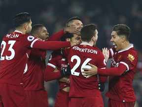 Liverpool players celebrate with Mohamed Salah, center, after he scored his side's fourth goal during the English Premier League soccer match between Liverpool and Manchester City at Anfield Stadium, in Liverpool, England, Sunday Jan. 14, 2018. Salah scored the wining goal.