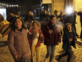 Children smoke while walking with a music band in the village of Vale de Salgueiro, northern Portugal, during the local Kings' Feast Friday night, Jan. 5, 2018. The village's Epiphany celebrations, called Kings' Feast, feature a tradition that each year causes an outcry among outsiders: parents encourage their children, some as young as 5, to smoke cigarettes.