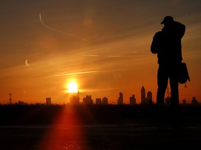 A man watches the sun rise over the buildings of the banking district in Frankfurt, Germany, Tuesday, Jan. 30, 2018.