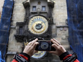 A woman takes a photo of the famed astronomical clock at the Old Town Square in Prague, Czech Republic, Monday, Jan. 8, 2018. Workers stopped the famous medieval astronomical clock on Monday and parts will be taken off site for months for major repairs. Prague officials say the clock installed on the City Hall's tower in 1410 will be completely disassembled and taken for its first comprehensive restoration since World War II.