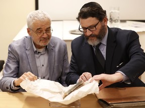 Daniel E. Kestenbaum, right, president of New York based auction house, hands over the book titled "Mikne Avram - Peculium Abrae" to director of Prague's Jewish Museum Leo Pavlat, left, in Prague, Czech Republic, Tuesday, Jan. 16, 2018. A rare 16th century book that used to belong to Prague's Jewish community before World War II and was considered lost has been returned after it reappeared at an auction held by Kestenbaum & Company auction house.