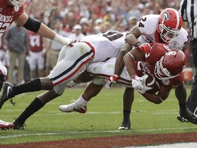 Oklahoma running back Rodney Anderson dives for a touchdown between Georgia defensive back J.R. Reed, left, and safety Dominick Sanders, right, during the first half of the Rose Bowl NCAA college football game, Monday, Jan. 1, 2018, in Pasadena, Calif.