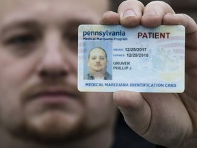 In this Wednesday, Jan. 10, 2018 photo Phil Gruver poses for a photograph with his Pennsylvania with his medical marijuana card in Emmaus, Pa. As gun-loving Pennsylvania becomes the latest state to operate a medical marijuana program, with the first dispensary on track to begin sales next month, authorities are warning patients that federal law bars marijuana users from having guns or ammunition. Gruver is weighing what to do with his .22-caliber rifle and a handgun he keeps for home defense.