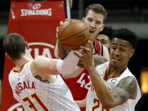 Toronto Raptors' Jakob Poeltl reaches for a loose ball against the Hawks' Mike Muscala and John Collins during the second quarter of their game in Atlanta on Wednesday night.