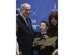 Israeli Prime Minister Benjamin Netanyahu, left, listens as Moshe Holtzberg, center, a young boy whose parents were killed during a 2008 terror attack reads a message during the unveiling of plans for a state-of-the-art Living Memorial in commemoration of the victims of the Mumbai attacks at the Chabad House in Mumbai, India, Thursday, Jan 18, 2018.