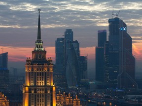 The skyscrapers of the Moscow International Business Centre, also known as Moscow City, right, stand beyond the Ukraine Radisson Royal hotel, left, illuminated at dusk in Moscow, Russia, on Tuesday, Oct. 28, 2014.