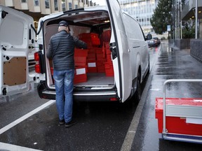 A staff member of the IOC unloads boxes with files at the Court of Arbitration for Sport (CAS) prior to the CAS hearing in the matter of 39 Russian athletes against the IOC, in Geneva, Switzerland, Monday, January 22, 2018. The CAS has opened a full week of appeal hearings for 39 Russian athletes disqualified from the 2014 Sochi Olympics for taking part in a state-backed doping program.