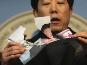 North Korean defector Park Sang-hak tears a portrait of North Korean leader Kim Jong Un during a press conference against the North Korea's participation in the 2018 Pyeongchang Winter Olympics at the National Assembly in Seoul, South Korea, Wednesday, Jan. 24, 2018. A team of South Korean officials travelled to North Korea on Tuesday to check logistics for joint events ahead of next month's Winter Olympics in the South, as the rivals exchanged rare visits to each other amid signs of warming ties.