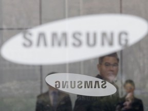 An employee walks past logos of the Samsung Electronics Co. at its office in Seoul, South Korea, Wednesday, Jan. 31, 2018. Samsung Electronics has reported a surge in quarterly earnings thanks to its record-breaking chip business.