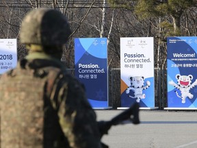 Posters showing the 2018 Pyeongchang Winter Olympic mascot are displayed as a South Korean army soldier stands guard at the Unification Observation post in Goseong, near the border with North Korea, South Korea, Friday, Jan. 19, 2018. The rival Koreas agreed Wednesday to form their first unified Olympic team and have their athletes parade together for the first time in 11 years during the opening ceremony of next month's Winter Olympics in South Korea, officials said.