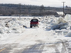 A vehicle drives between ice piled along the sides of Route 101 in Hoyt, N.B., on Sunday, January 14, 2018. Heavy rain flooded the road on Saturday floating large ice onto the road and dropping temperatures then froze the water overnight into Sunday morning.