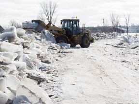 Tim McCann uses a front end loader to remove ice off of Route 101 in Hoyt, N.B., on Sunday, January 14, 2018. Heavy rain flooded the road on Saturday floating large ice onto the road and dropping temperatures then froze the water overnight into Sunday morning.