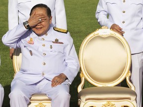 In this Dec. 4, 2017, photo, Deputy Prime Minister Prawit Wongsuwan raise his hand to shade the sun wearing a luxury watch and diamond ring during ceremony Government house. Prawit has so far been spotted wearing a total of 25 opulent time-pieces, none of which appears on his last declaration of assets.