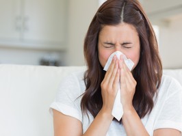 Brunette sneezing in a tissue in the living room