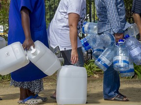 People queue to collect water from a natural spring outlet in the South African Breweries in Cape Town, Tuesday Jan. 23, 2018.