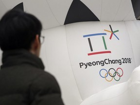 In this Dec. 29, 2017, photo, a man walks by the official emblem of the 2018 Pyeongchang Olympic Winter Games, in downtown Seoul, South Korea.