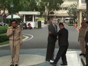 In this image from video, Thailand's Prime Minister Prayuth Chan-ocha, left, talks to the media as a life-sized cardboard cut-out figure of himself is carried into view by an aid, in Bangkok, Thailand, Monday Jan. 8, 2018.