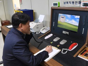 FILE - In this Jan. 3, 2018 file photo, a South Korean government official communicates with a North Korean officer during a phone call on the dedicated communications hotline at the border village of Panmunjom in Paju, South Korea. A Seoul official says both Koreas have agreed to hold their first talks in more than two years next Tuesday, Jan. 9, 2018. Unification Ministry spokesman Baik Tae-hyun said Friday, Jan. 5, 2018,  that North Korea has accepted Seoul's offer to meet at the border village of Panmunjom that day to discuss how to cooperate on next month's Winter Olympics and how to improve overall ties.(South Korea Unification Ministry/Yonhap via AP, File)