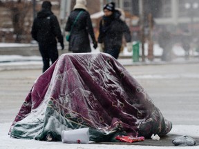 January 2, 2013 - A homeless person huddles under a blanket on top of a steamy subway grate on a cold winter day in Toronto, Ontario, January 2, 2013.