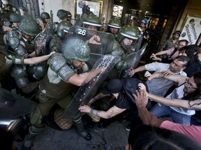 In this Jan. 5, 2018 photo, protesters try to liberate a woman detained by riot police during a protest commemorating the ten year anniversary of the police killing of Mapuche indigenous activist Matias Catrileo, Santiago, Chile. Catrileo was shot to death on Jan. 3, 2008 by a police officer during a land dispute in southern Chile. The officer was sentenced to three years in jail, but served his time on probation. The officer was eventually removed from the police force.