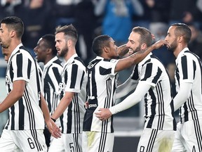 Juventus' Douglas Costa, center, embraces teammate Gonzalo Higuaín, second from right, as he celebrates scoring the opening goal during the Italian Serie A soccer match between Juventus and Genoa, at the Allianz stadium in Turin, Italy, Monday, Jan. 22, 2018.