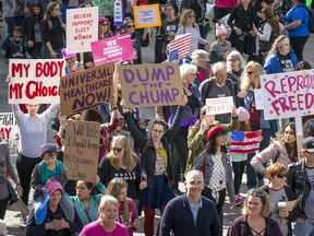 FILE - In this Saturday, Jan. 20, 2018 file photo, demonstrators hold signs during a Women's March in Austin, Texas, on the anniversary of President Donald Trump's inauguration. On the anniversary of President Donald Trump's inauguration, people participating in rallies and marches in the U.S. and around the world Saturday denounced his views on immigration, abortion, LGBT rights, women's rights and more.