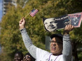 Priscilla Owens waves a flag and holds up items featuring Dr. Martin Luther King, Jr., during an MLK parade on Monday, Jan. 15, 2018, in Houston.