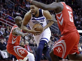 Minnesota Timberwolves center Karl-Anthony Towns (32) drives between Houston Rockets forward Luc Mbah a Moute (12) and center Clint Capela (15) during the first half of an NBA basketball game Thursday, Jan. 18, 2018, in Houston.