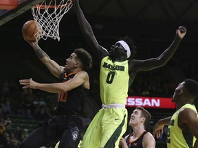 Oklahoma State guard Jeffrey Carroll, left, scores past Baylor forward Jo Lual-Acuil Jr., right, in the first half of an NCAA college basketball game, Monday, Jan. 15, 2018, in Waco, Texas.