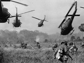 Hovering U.S. Army helicopters pour machine gun fire into the tree line to cover the advance of South Vietnamese ground troops in a March 1965 photo by award-winning photographer Horst Faas.