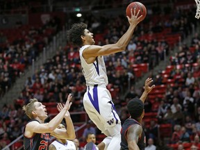 Washington guard Matisse Thybulle, center, goes to the basket as Utah's Tyler Rawson (21) and Justin Bibbins, right, defend in the first half during an NCAA college basketball game Thursday, Jan. 18, 2018, in Salt Lake City.