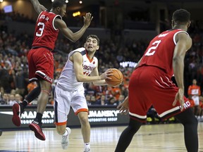 Virginia's Ty Jerome (11) ducks underneath North Carolina State's Lavar Batts, Jr. (3) in the first half of an NCAA college basketball game Sunday, Jan. 14, 2018, in Charlottesville, Va.