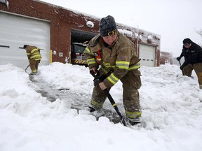 Lt. Charlene Beach, center, and other firefighters clear snow from the driveways at Fire Station No. 4 in Chesapeake, Va., during the snowstorm on Thursday, Jan. 4, 2018.