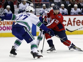 Washington Capitals center Lars Eller (20), from Denmark, shoots the puck past Vancouver Canucks defenseman Ben Hutton (27) for a goal during the first period of an NHL hockey game, Tuesday, Jan. 9, 2018, in Washington.