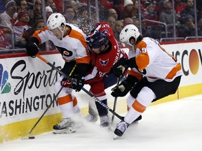 Philadelphia Flyers defenseman Robert Hagg, left, from Sweden, and center Nolan Patrick, right, combine on Washington Capitals left wing Andre Burakovsky, from Austria, during the first period of an NHL hockey game Wednesday, Jan. 31, 2018, in Washington.