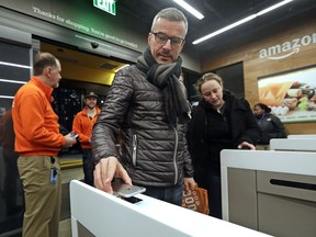 A customer scans his Amazon Go cellphone app at the entrance as he heads into an Amazon Go store, Monday, Jan. 22, 2018, in Seattle. The store, which opened to the public on Monday, allows shoppers to scan their smartphone with the Amazon Go app at a turnstile, pick out the items they want and leave. The online retail giant can tell what people have purchased and automatically charges their Amazon account.