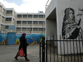 A Palestinian woman walks outside a United Nations' school at the Dheisheh refugee camp, near Bethlehem, in the West Bank, on Jan. 17, 2018.