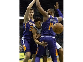 Milwaukee Bucks guard Malcolm Brogdon, center, is defended by Phoenix Suns forward Dragan Bender, left, and Greg Monroe, right, during the first half of an NBA basketball game Monday, Jan. 22, 2018, in Milwaukee.