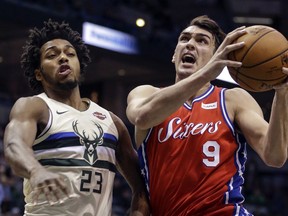 Milwaukee Bucks' Sterling Brown, left, tries to stop Philadelphia 76ers' Dario Saric on his way in for a lay-up during the first half of an NBA basketball game Monday, Jan. 29, 2018, in Milwaukee.