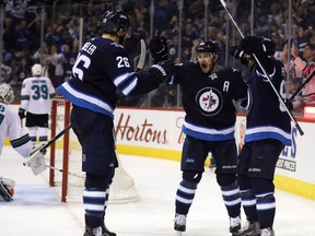 Winnipeg Jets' Blake Wheeler (26), Bryan Little (18) and Mathieu Perreault (85) celebrate after Perreault scored on San Jose Sharks goaltender Martin Jones (31) during second period NHL hockey action in Winnipeg, Sunday, January 7, 2018.