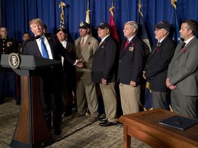 FILE - In this Nov. 10, 2017, file photo, President Donald Trump is flanked by veterans at an event to sign a proclamation honoring veterans at the Hyatt Regency Danang Resort in Danang, Vietnam. Trump is again claiming more success than reality in improving veterans care, touting initiatives that have yet to show meaningful impact and glossing over bigger unfulfilled campaign promises.