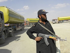 FILE - In this Oct. 1, 2010, file photo, a Pakistani border guard stands alert as NATO trucks carry fuel, proceed to neighboring Afghanistan at Pakistani border post Chaman. As bad as President Donald Trump sees U.S.-Pakistani ties, they can get far worse. Over 16 years that included deadly U.S. drone strikes and accusations Pakistan helps insurgents that kill Americans, the reluctant allies never reached one point of no return: Pakistan closing air routes to Afghanistan.