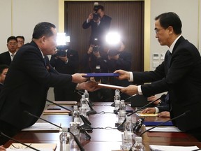 South Korean Unification Minister Cho Myoung-gyon, right, exchanges documents with the head of North Korean delegation Ri Son Gwon during their meeting at the Panmunjom in the Demilitarized Zone in Paju, South Korea, Tuesday, Jan. 9, 2018. The rival Koreas took steps toward reducing their bitter animosity during rare talks Tuesday, as North Korea agreed to send a delegation to next month's Winter Olympics in South Korea and reopen a military hotline. (Korea Pool via AP)