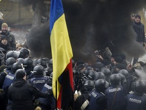Protesters with a Ukrainian national flag burn tires while clashing with police during a rally outside the Supreme Rada in Kiev, Ukraine, Tuesday, Jan. 16, 2018.  At least one policeman has been injured and several protesters have been detained during scuffles outside the Ukrainian parliament to protest a new law governing the areas in the country's east under separatist control.