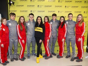 Russian speed skaters and pose for a photo with Russian outfit company Zasport designer Anastasia Zadorina, center, pose for a photo in the red-and-white and grey-and-white tracksuits, as well as grey coats are modified from the original designs drawn up for Team Russia as potential Olympians. in Moscow, Russia, Monday, Jan. 22, 2018. As a punishment in fallout from the Sochi scandal, Russia has been denied using its flag and badges which are replaced with IOC-approved symbols. Instead of the Russian Olympic Committee logo, there's now a white circle on the chest with the red inscription "Olympic Athlete from Russia."