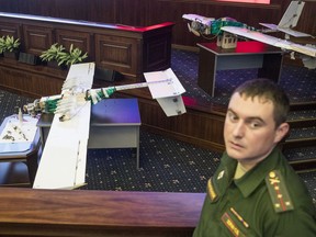 A Russian officer stands next to drones that attacked the Russian air base in Syria and were captured by the Russian military are displayed at a briefing in the Russian Defense Ministry in Moscow, Russia, Thursday, Jan. 11, 2018. Saturday's, Jan.6, 2018 raid against the Hemeimeem air base and a Russian naval facility in Tartus involved 13 drones, seven of the drones were shot down by air defense systems and the remaining six were forced to land, according to the Russian Defense Ministry.