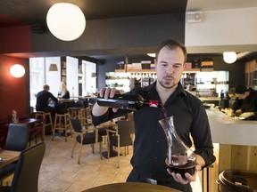 In this photo taken on Saturday, Jan. 20, 2018, a restaurant worker pours wine into decanter as bottles from Jan. 1, 2018 are no longer allowed to be displayed in restaurants after 8pm as the labels are considered advertising at the restaurant in Vilnius, Lithuania. Lithuania's new liquor law has increased the legal drinking age from 18 to 20, banned alcohol advertising and drastically curtailed opening hours for liquor stores.